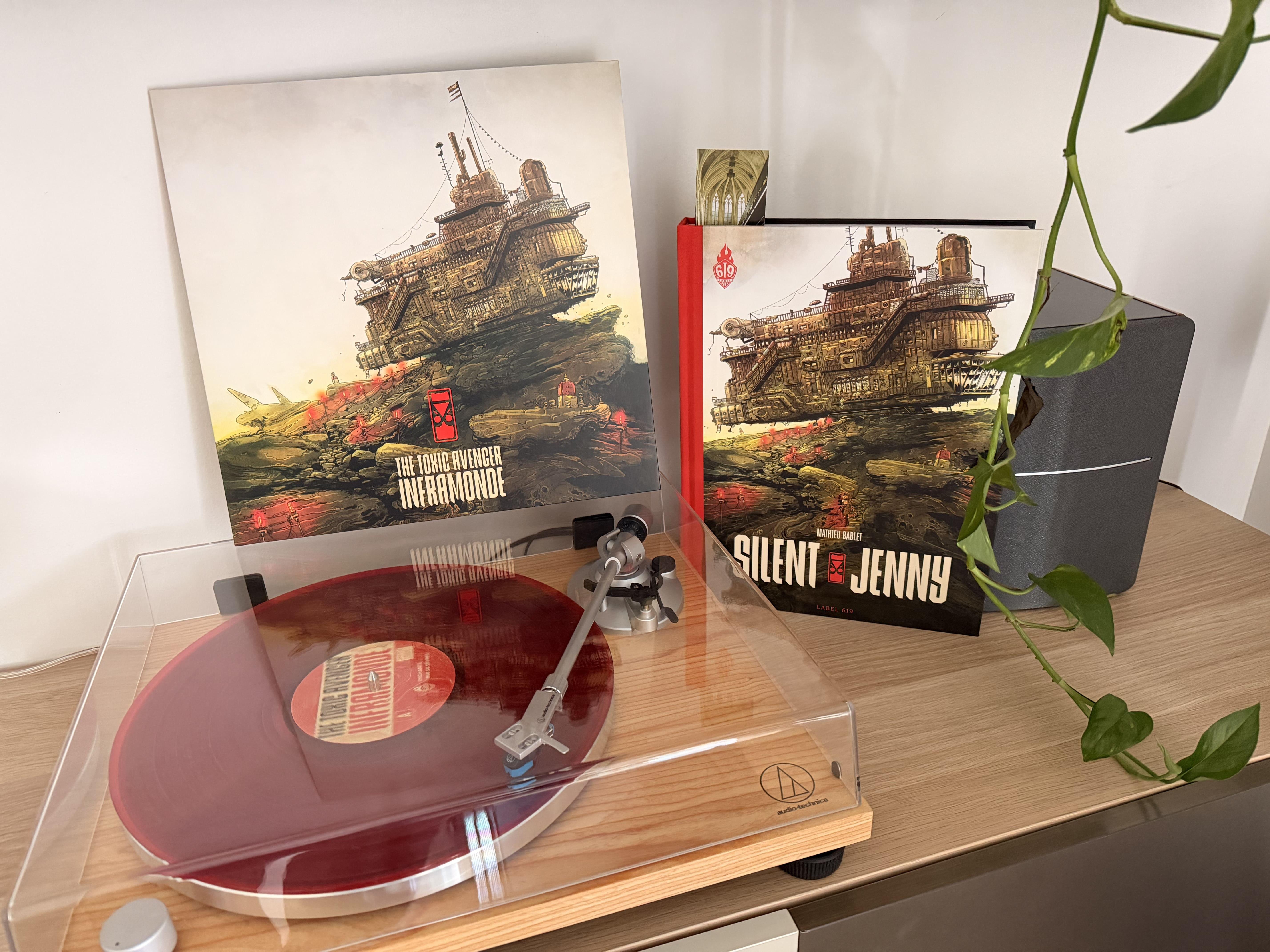 Le vinyle rouge d’Inframonde, de The Toxic Avenger, sur une platine Audio-Technica, devant la pochette de l’album et l’édition reliée de Silent Jenny de Mathieu Bablet — les deux partagent la même illustration